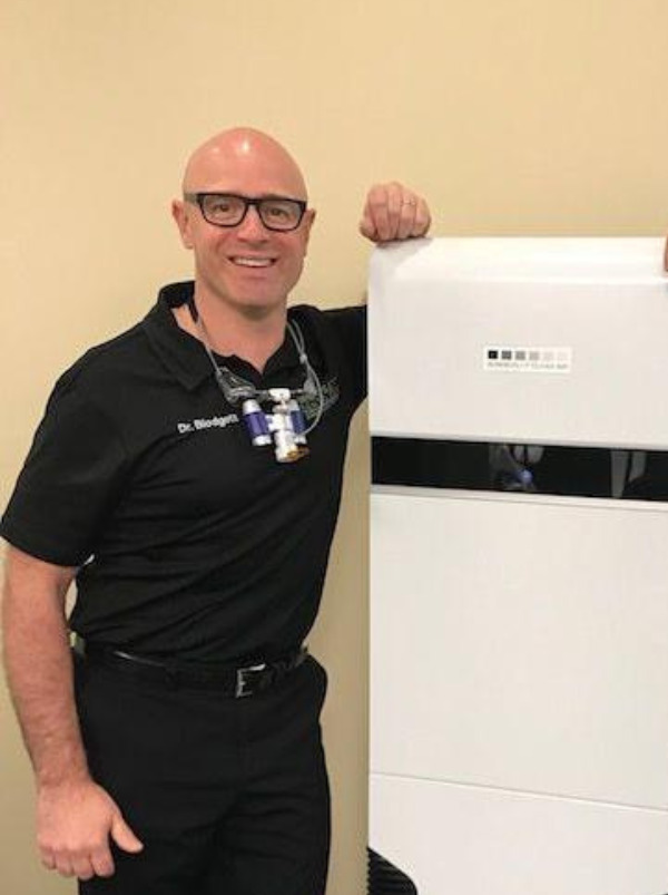 Dr. Kelly Blodgett & Dr. Bryan Neish stand proudly next to one of the many "Surgically Clean Air" units located in Blodgett Dental Care